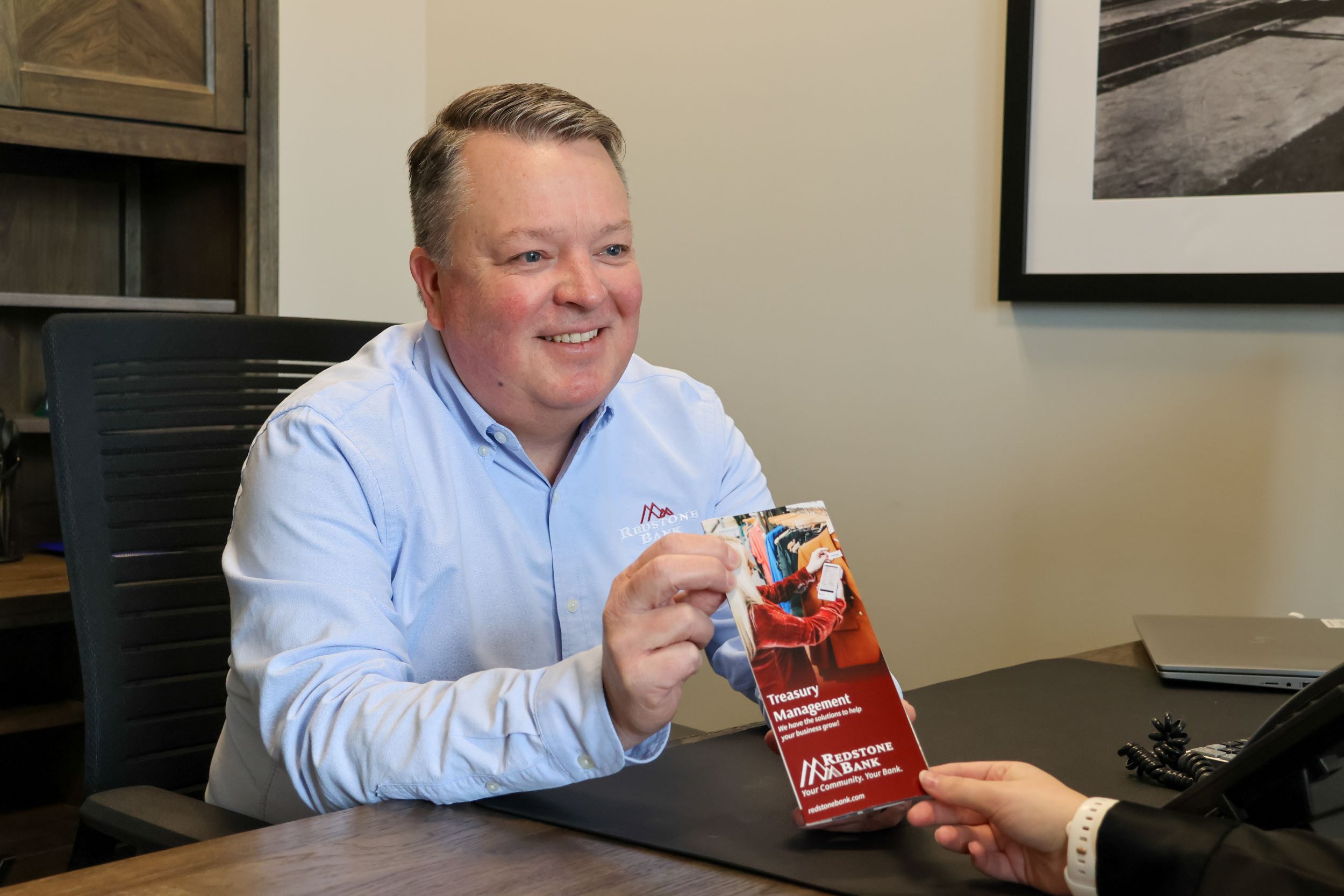 Heath Kinsland handing a brochure to a client in his office
