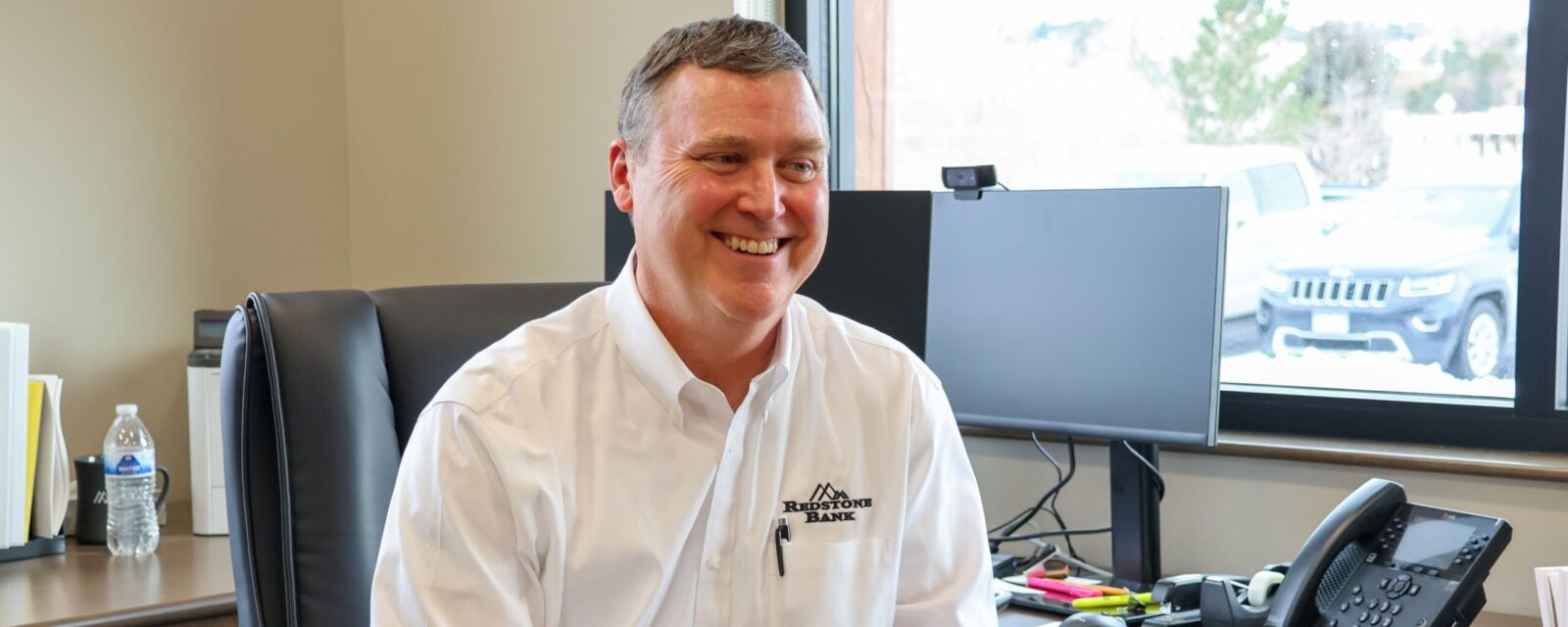 Jason Whyte, Treasury Management officer sitting at his desk smiling