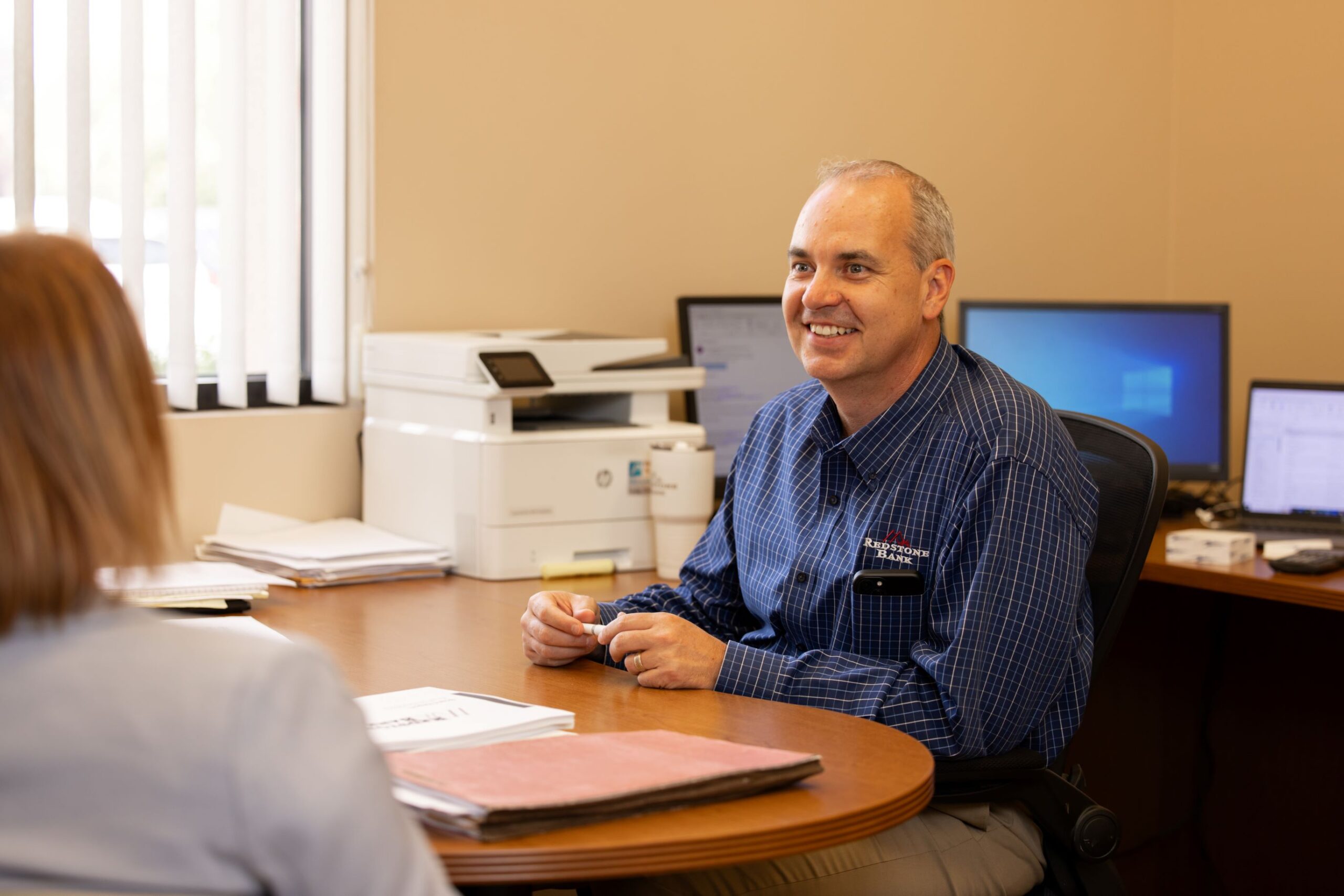 Josh, loan officer at our Centennial Branch talks to a customer at his desk.