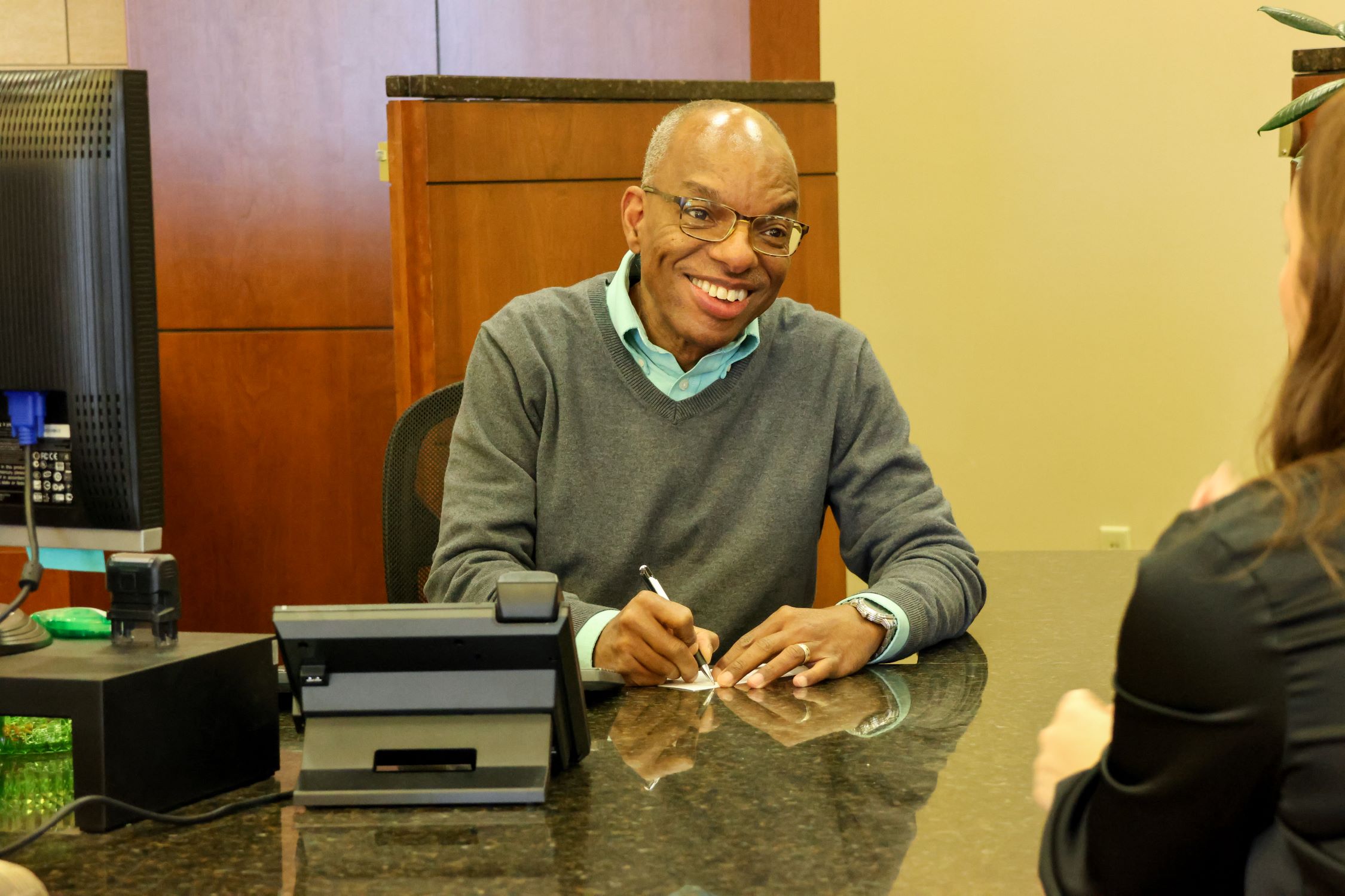 Ken Holmes sitting at his desk, smiling at a customer