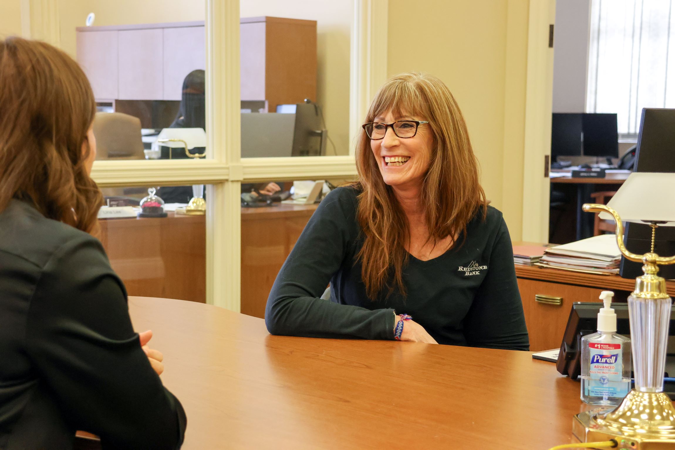 Shelley Greene, loan officer, visiting with a client at her desk